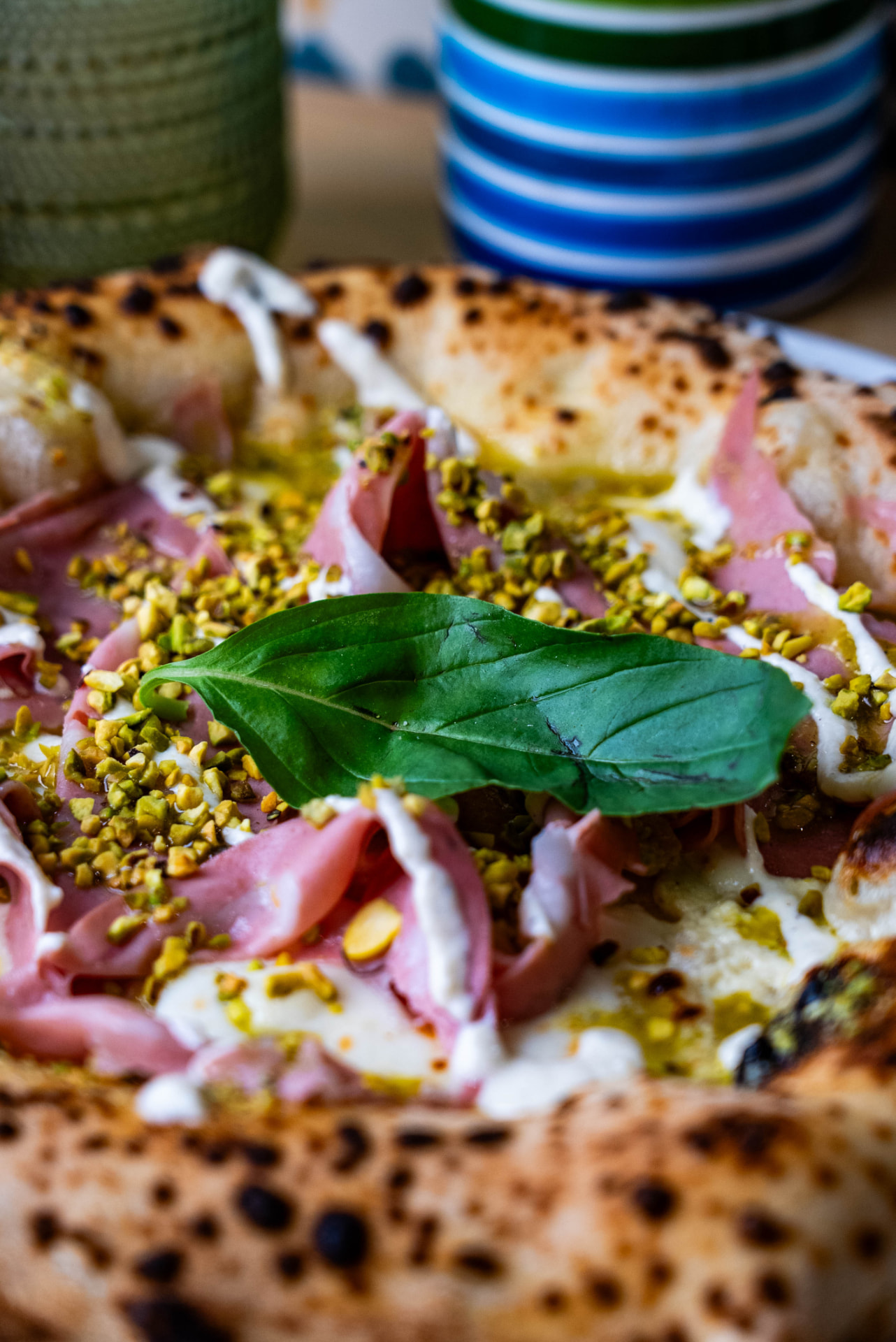 Pizza à la mortadelle et pistaches, feuille de basilic
